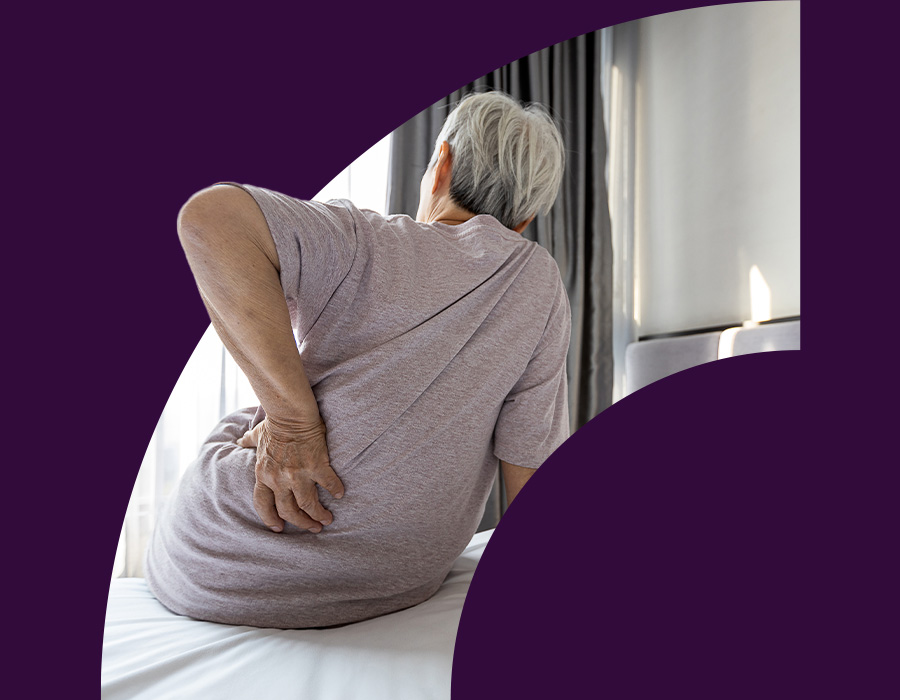 Old woman holding her back sitting on bed