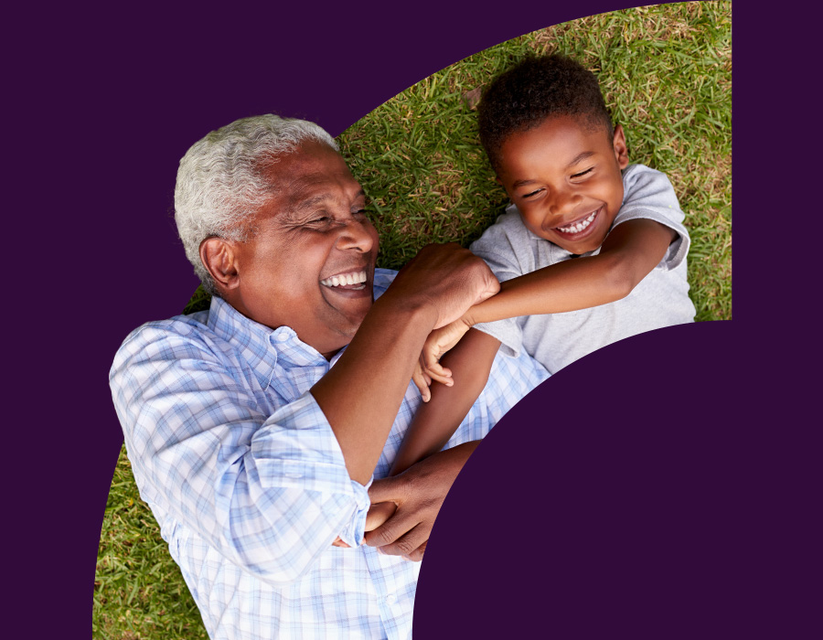 Black grandfather playing with his grandson on the lawn