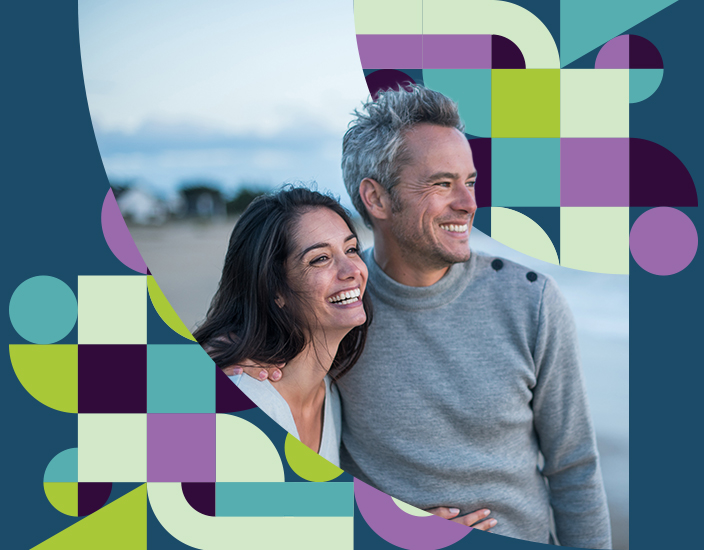 Young couple at beach smiling and looking at the ocean
